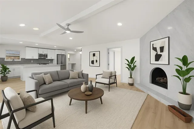 a living room with furniture a potted plant and kitchen view