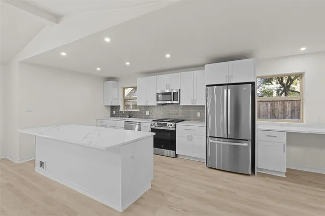 a kitchen with white cabinets and stainless steel appliances