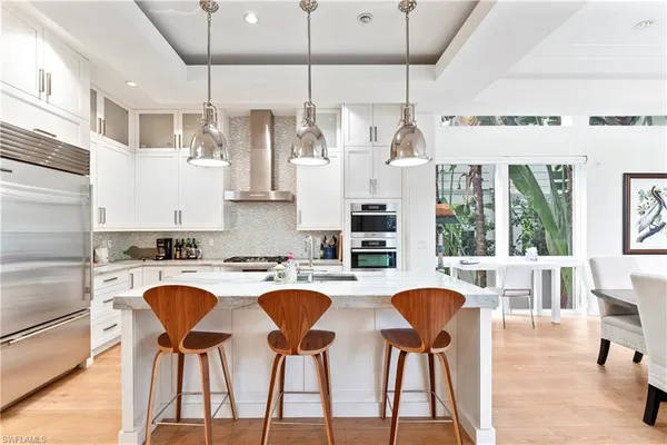 a kitchen with stainless steel appliances granite countertop a table chairs and a wooden floor