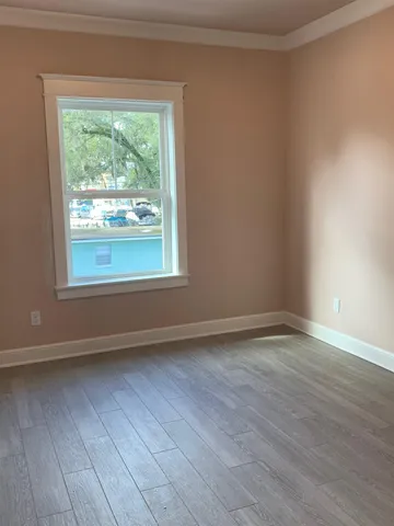 a view of an empty room with wooden floor and a window