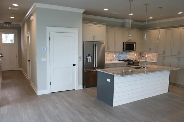 a kitchen with stainless steel appliances kitchen island granite countertop a refrigerator and a sink