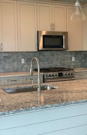 a kitchen with granite countertop white cabinets and stainless steel appliances