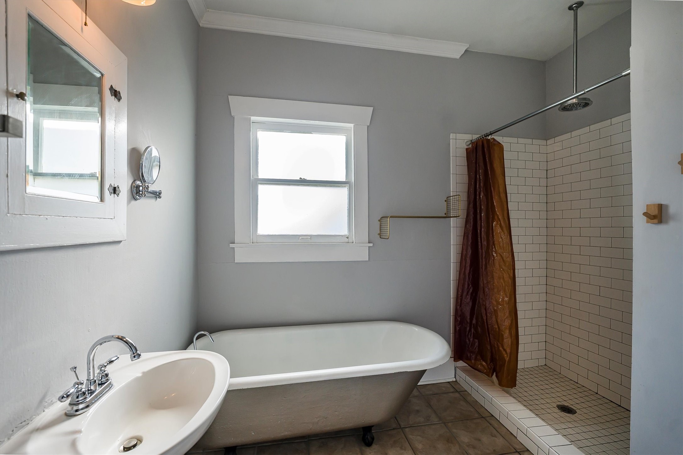 210 Tabor Street Houston, TX 77009 - Photo 9 of 18 Charming bathroom with a vintage clawfoot tub, walk-in shower, and a single sink. The neutral color scheme and natural light from the window create a bright, inviting space.