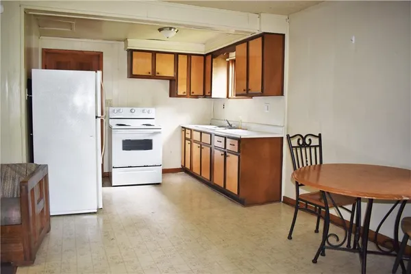 a kitchen with stainless steel appliances a stove a sink refrigerator and a chair
