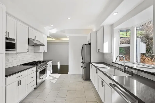 a large kitchen with stainless steel appliances granite countertop a sink stove and refrigerator