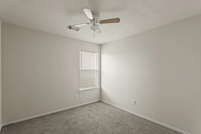 an empty room with ceiling fan and window
