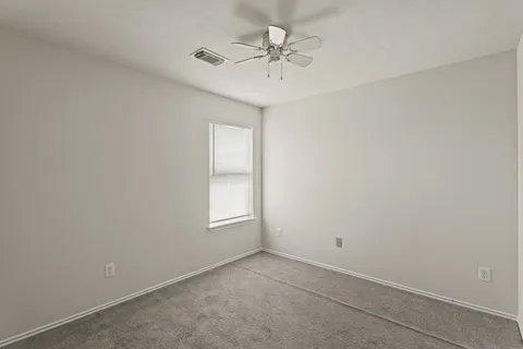 an empty room with a chandelier fan and windows