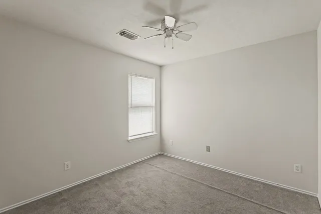 an empty room with a chandelier fan and windows