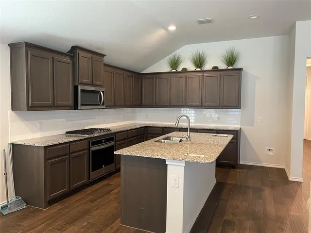 a kitchen with a sink and a stove top oven with wooden floor