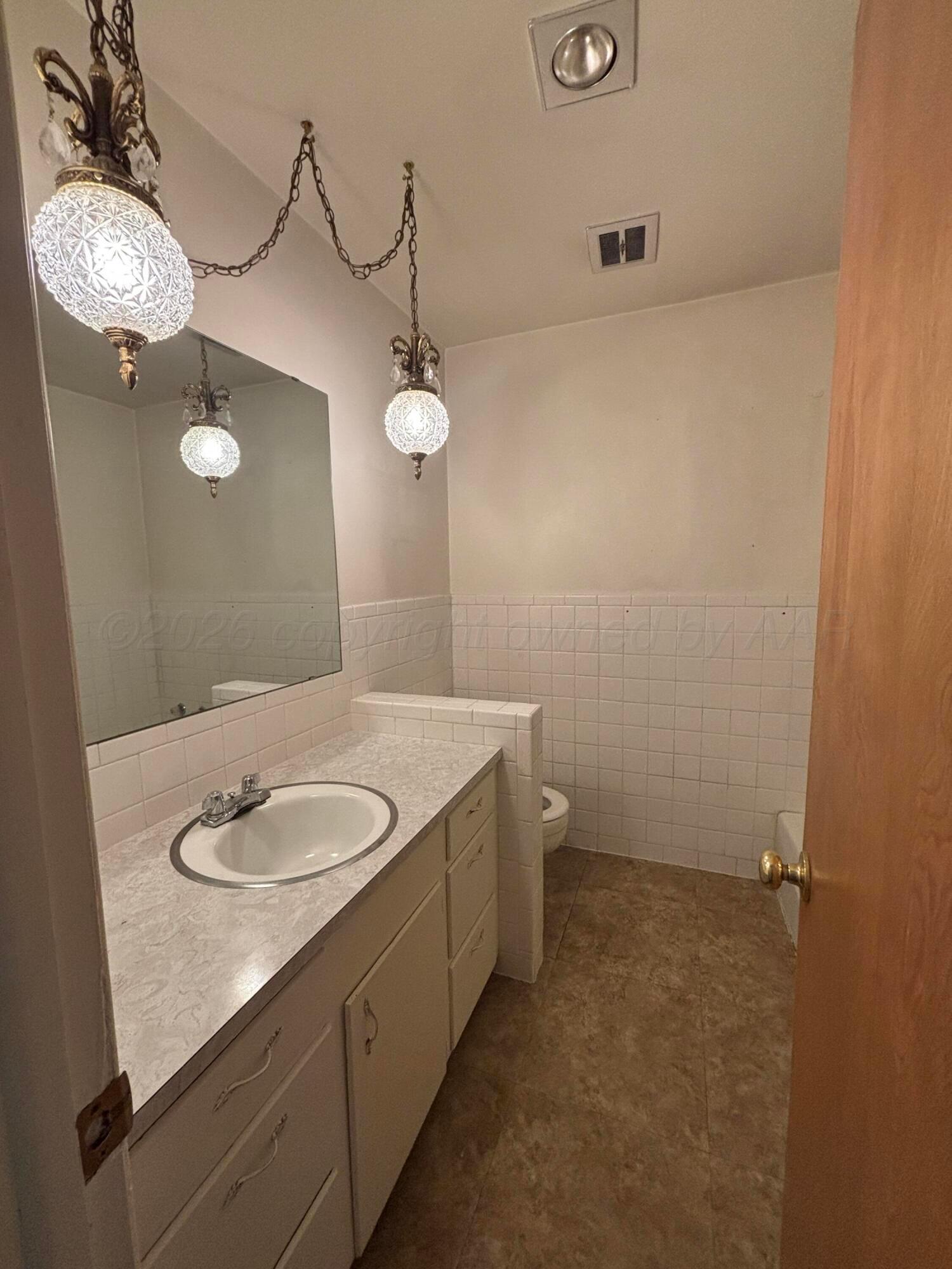 442 Harvey Street Miami, TX 79059 - Photo 13 of 19 a bathroom with a granite countertop sink a light fixture and a mirror