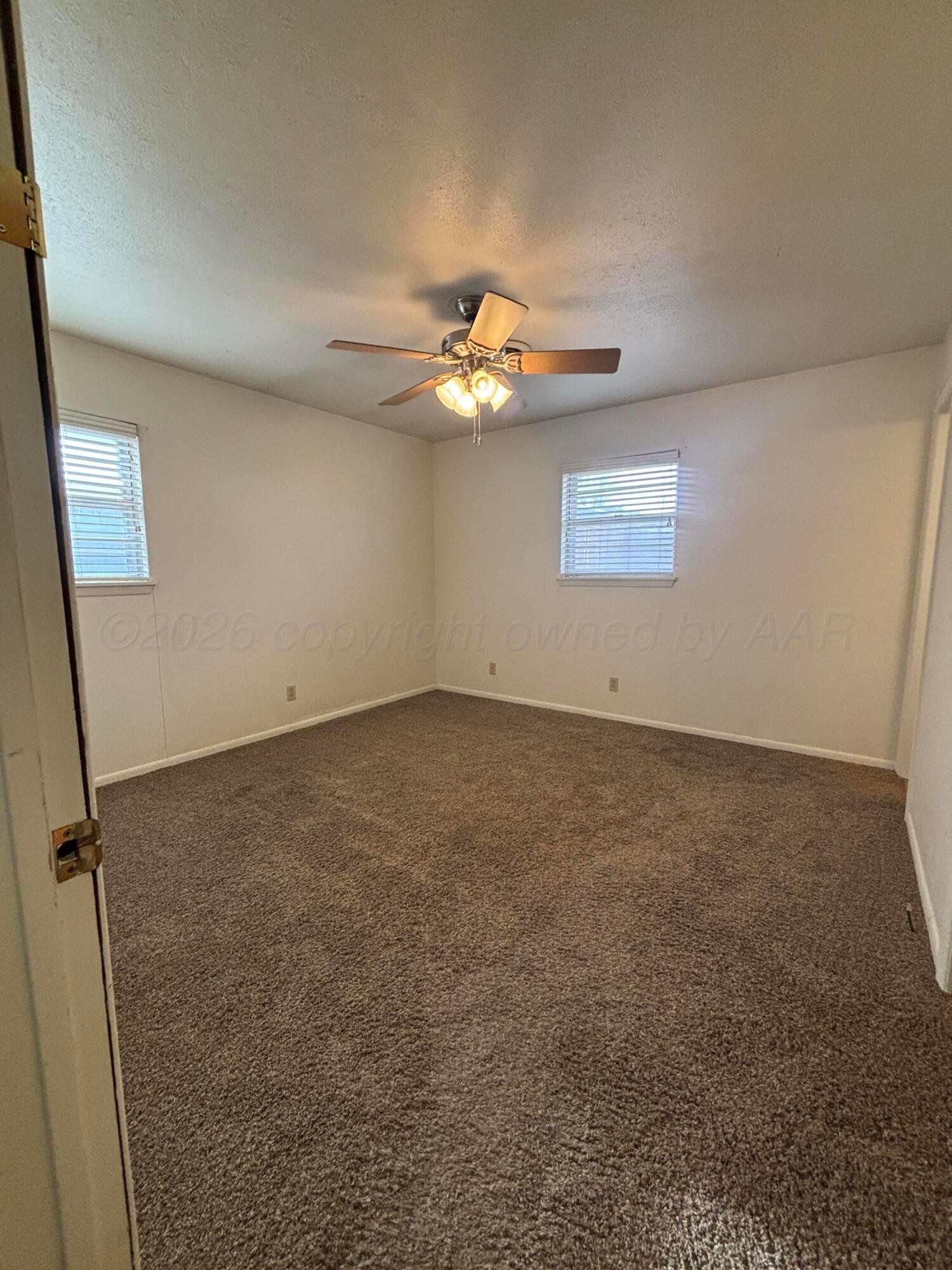 442 Harvey Street Miami, TX 79059 - Photo 6 of 19 an empty room with a chandelier fan and windows