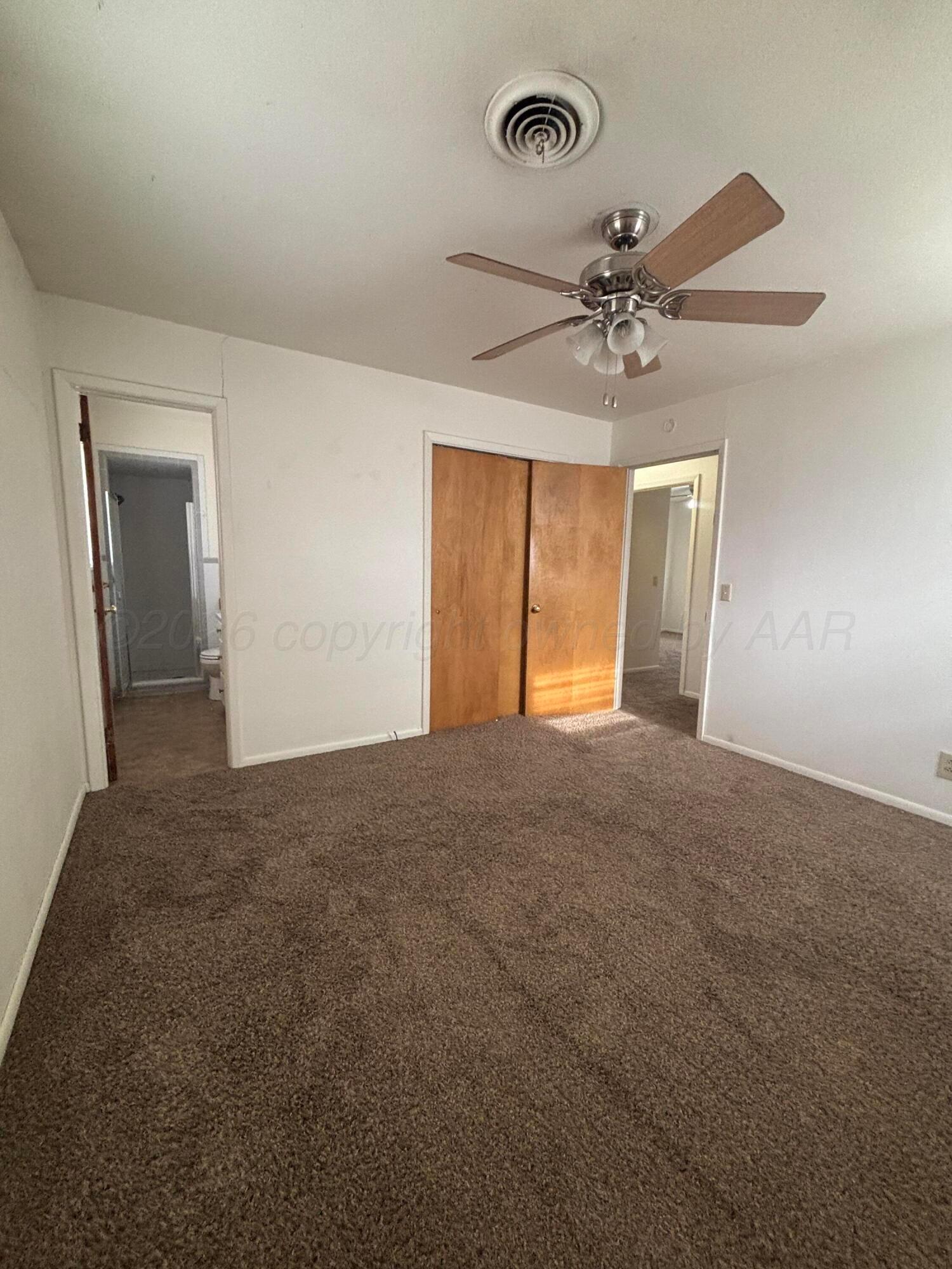 442 Harvey Street Miami, TX 79059 - Photo 8 of 19 an empty room with a chandelier fan and windows