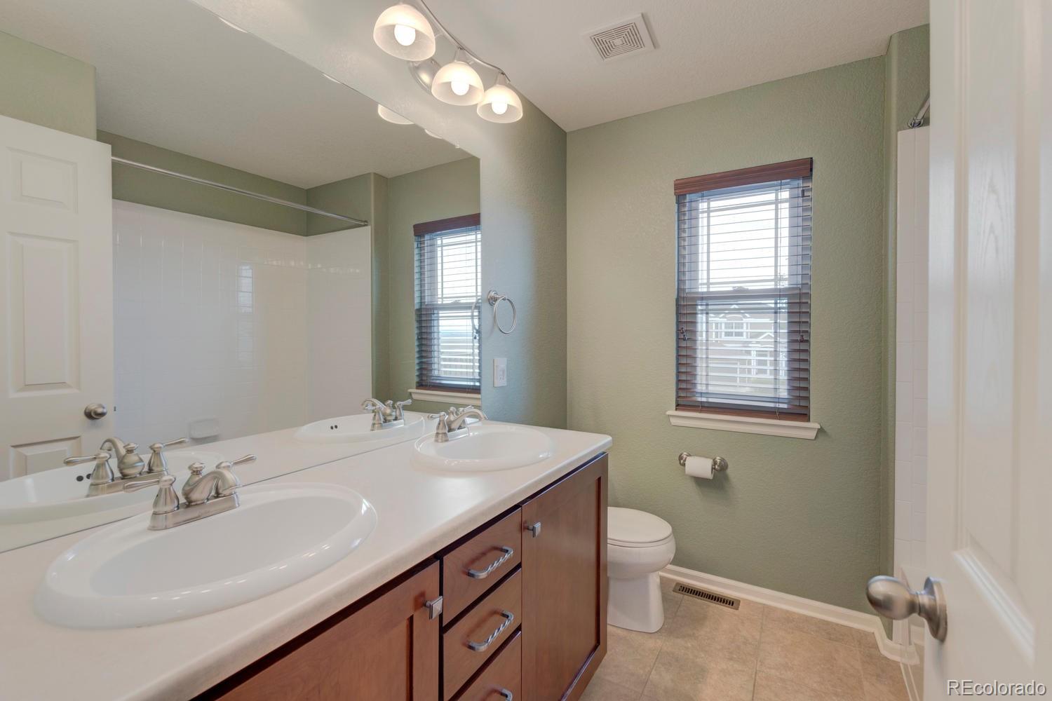 4939 Silver Feather Circle Broomfield, CO 80023 - Photo 27 of 35 a bathroom with a granite countertop sink a toilet and a mirror