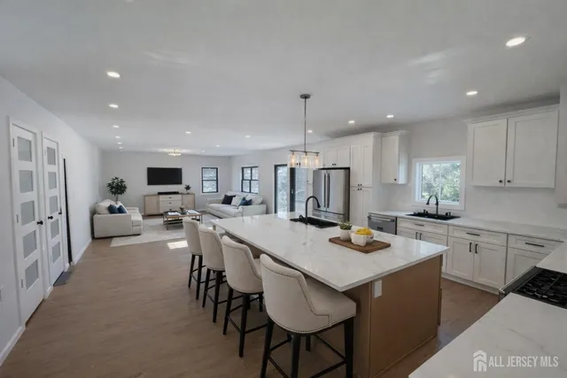 a kitchen with stainless steel appliances granite countertop a table chairs refrigerator and sink