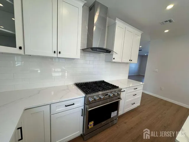 a kitchen with stainless steel appliances granite countertop a stove and a white cabinets