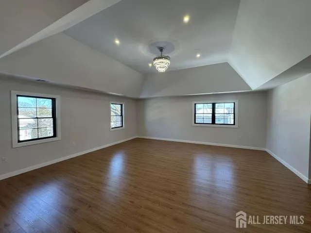 a spacious bedroom with a bed and wooden floor