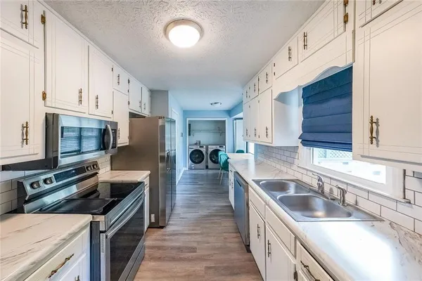 a kitchen with granite countertop a sink wooden cabinets and stainless steel appliances