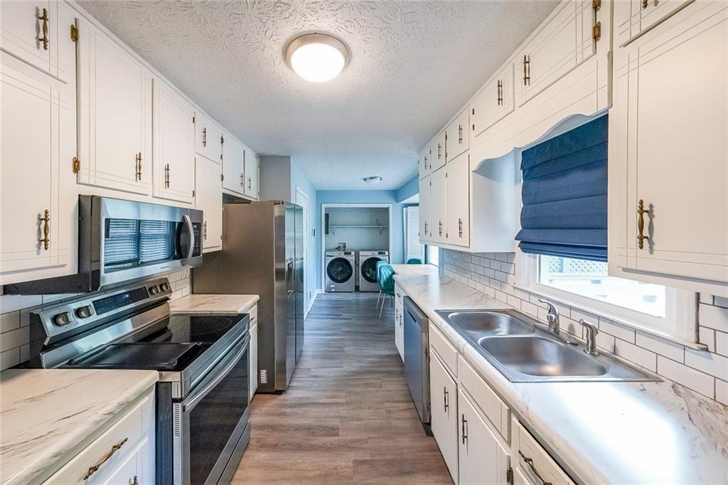 820 Bridgewater Way Southeast Conyers, GA 30094 - Photo 5 of 19 a kitchen with granite countertop a sink wooden cabinets and stainless steel appliances