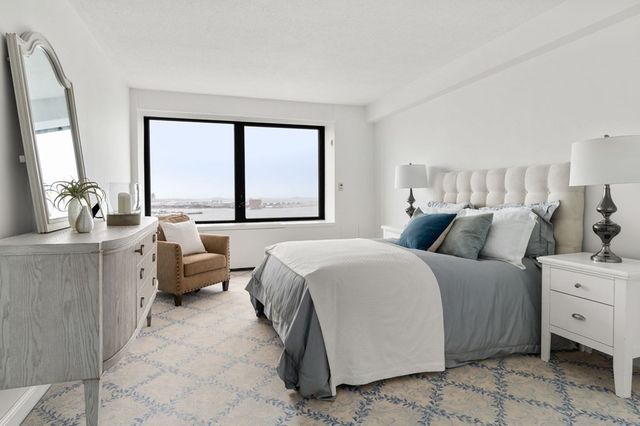 a bedroom with a bed and large windows