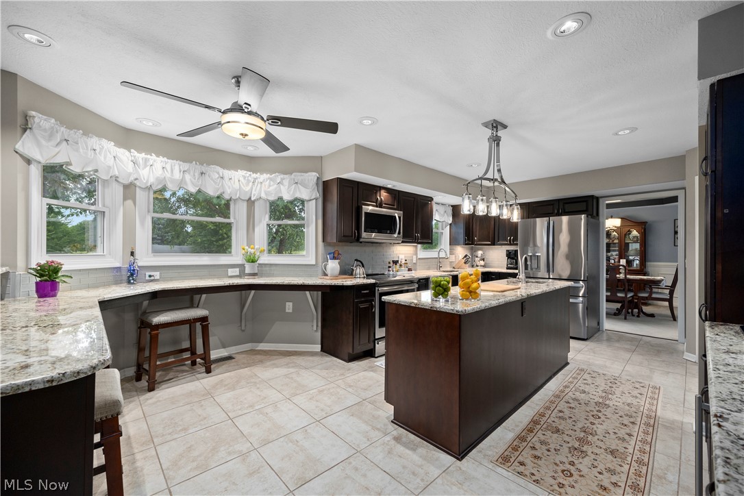 3270 North Ridge Road Vermilion, OH 44089 - Photo 16 of 49 Kitchen featuring a center island, recessed lighting, tile flooring, dark wood cabinetry, and stainless steel appliances