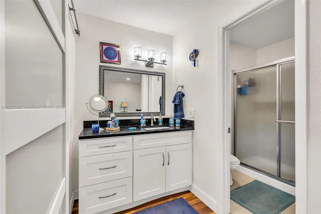 a en suite bathroom with a granite countertop sink and a mirror