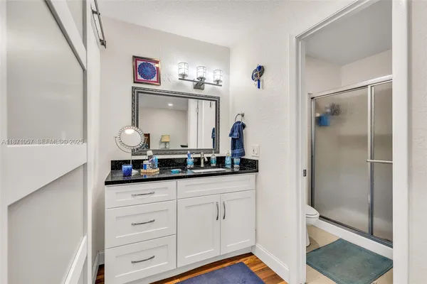 a en suite bathroom with a granite countertop sink and a mirror