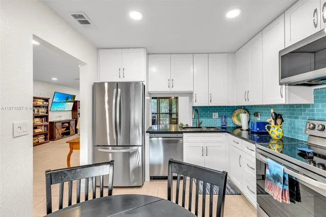 a kitchen with stainless steel appliances granite countertop a refrigerator a stove top oven a sink and dishwasher