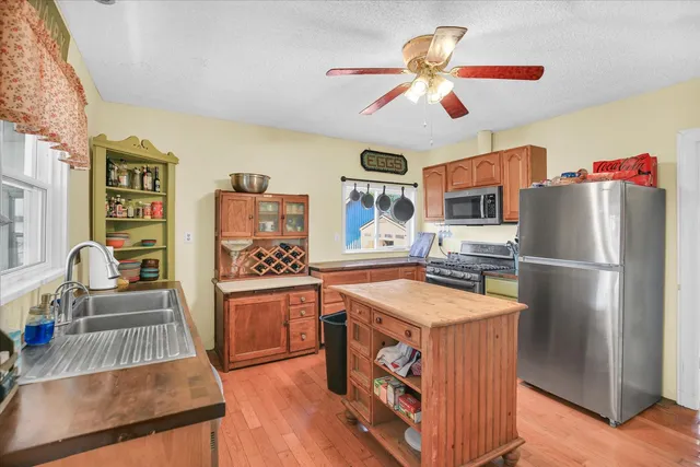 a kitchen with stainless steel appliances granite countertop a refrigerator a stove and a sink with couches