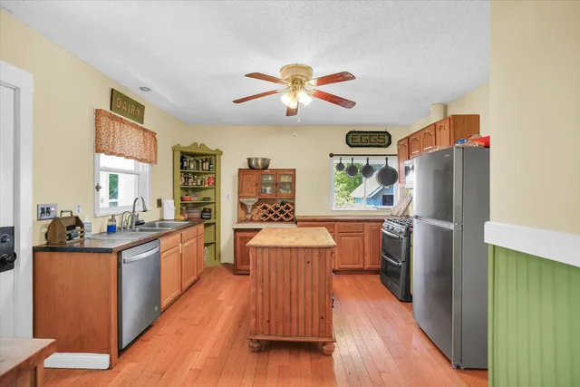 a kitchen with a refrigerator a stove top oven a sink dishwasher and wooden floor