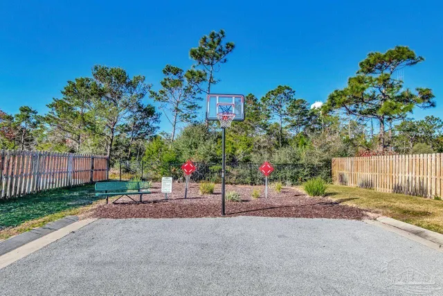 a view of a street with flower plants and wooden fence