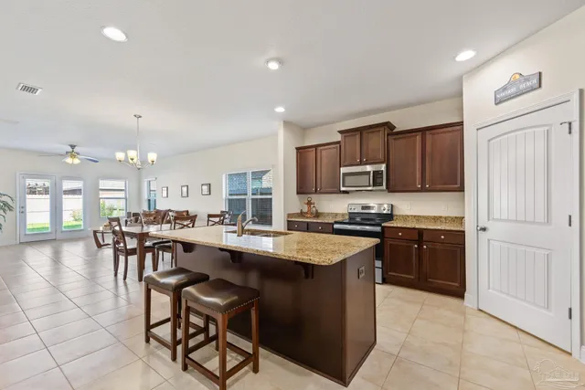 a kitchen with stainless steel appliances granite countertop wooden cabinets a stove a sink a dining table and chairs