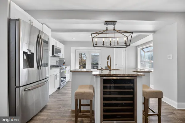 a kitchen with stainless steel appliances a dining table chairs refrigerator and cabinets