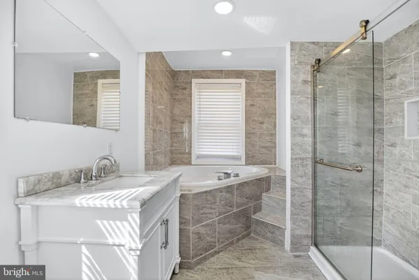a bathroom with a tub sink and mirror