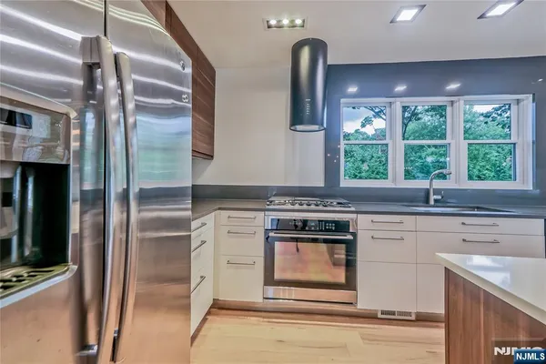 a kitchen with stainless steel appliances granite countertop a stove a refrigerator and a sink