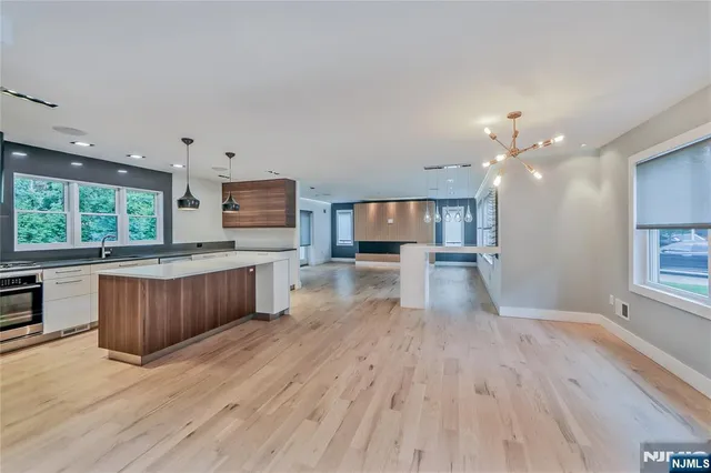 a kitchen with stainless steel appliances kitchen island wooden floors wooden cabinets and entryway