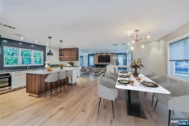 a open dining room with kitchen island furniture a chandelier wooden floor and a view