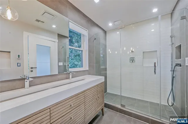 a bathroom with a double vanity sink mirror and shower