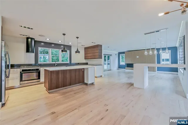 a large kitchen with stainless steel appliances kitchen island granite countertop a large counter top and wooden floors