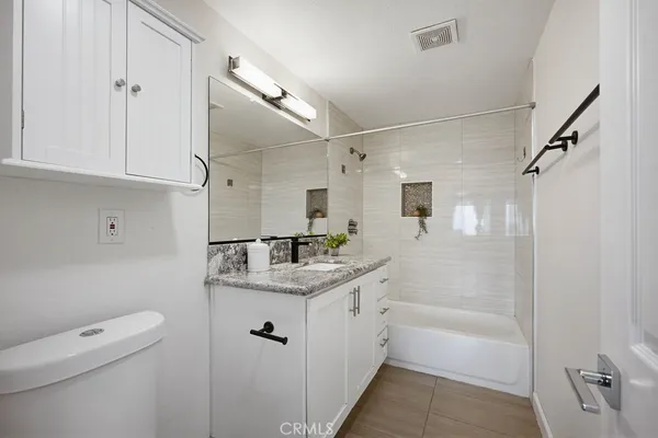 a bathroom with a granite countertop sink a toilet and shower