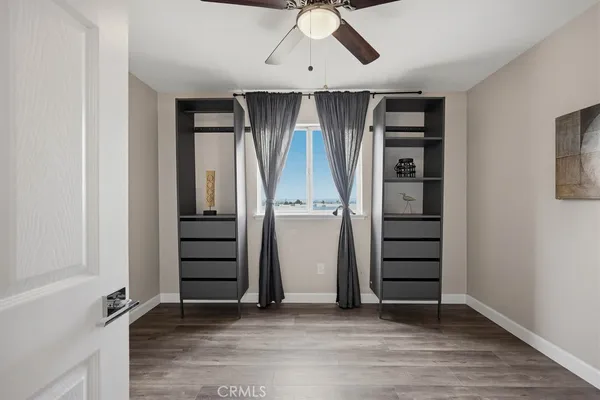 an empty room with wooden floor closet and windows