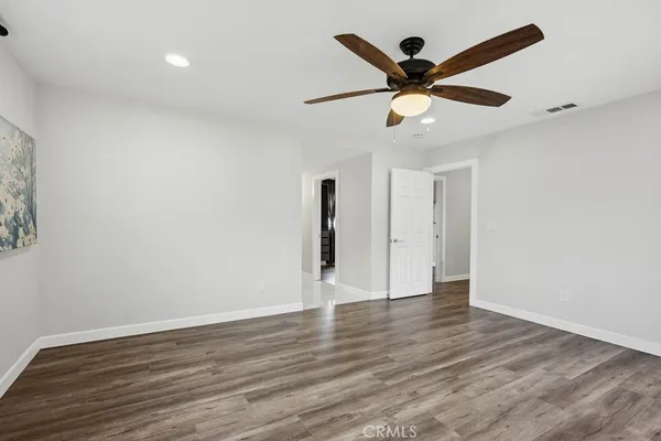 an empty room with wooden floor and ceiling fan