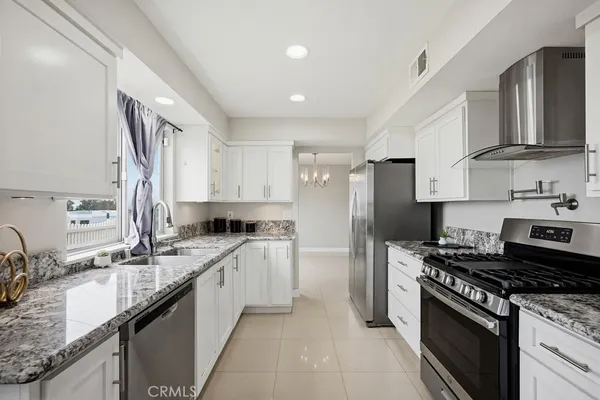 a kitchen with stainless steel appliances granite countertop a sink stove refrigerator and cabinets