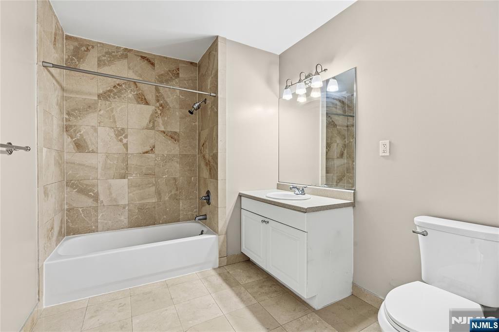 905 River Road, Unit 312 Edgewater, NJ 07020 - Photo 14 of 33 a bathroom with a granite countertop sink a toilet and bathtub