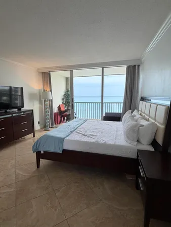 a bedroom with a bed chair and a flat tv screen on the dresser