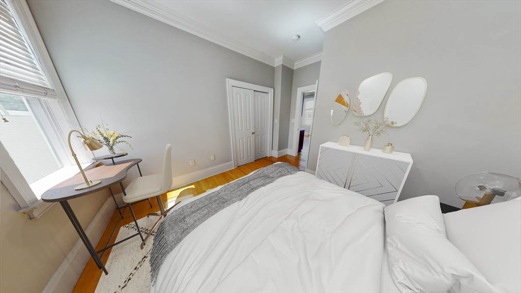 30-32 Ward Street, Unit 2 Boston, MA 02127 - Photo 11 of 14 a bedroom with a bed a chandelier with the mirror and vanity