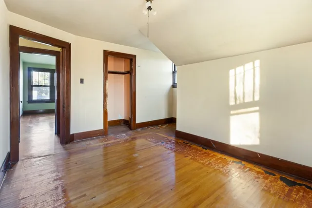 an empty room with wooden floor and windows