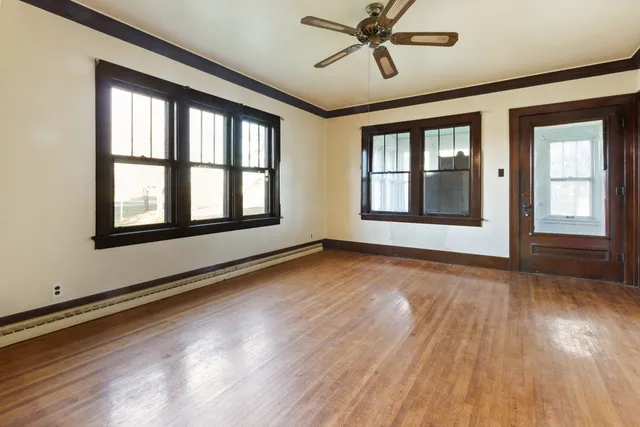a view of an empty room with wooden floor and a window
