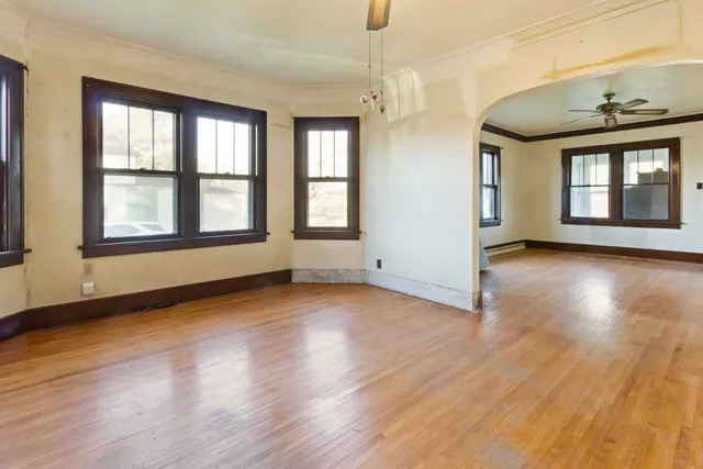 an empty room with wooden floor and windows