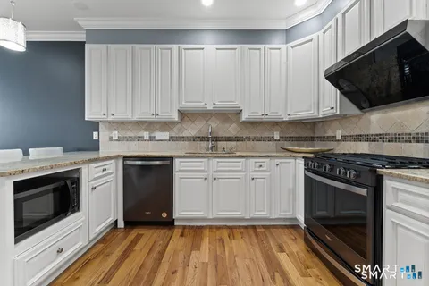a kitchen with stainless steel appliances granite countertop a stove a sink and a microwave