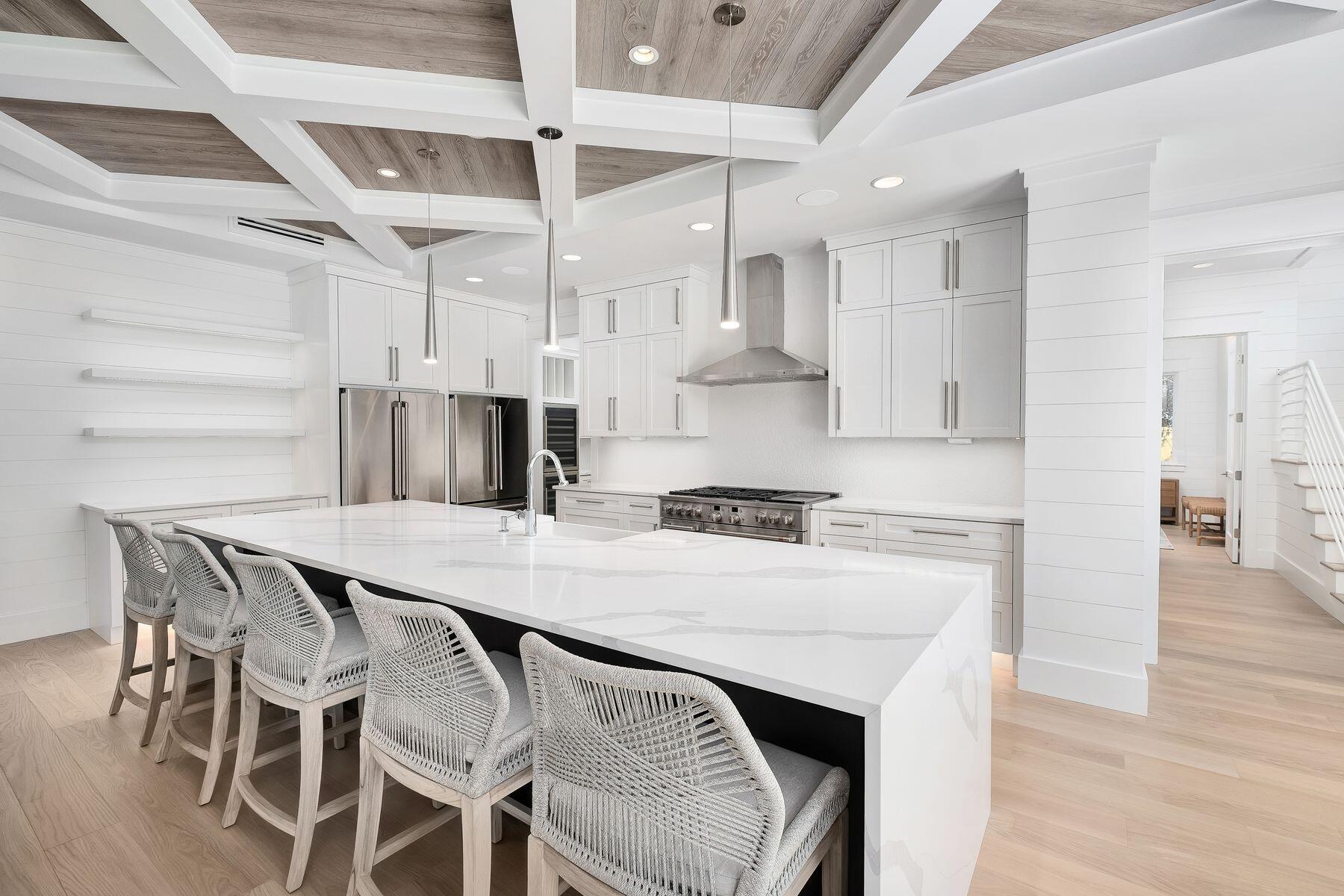 56 Pelican Glide Lane Seacrest, FL 32461 - Photo 12 of 55 a kitchen with stainless steel appliances granite countertop a stove a refrigerator a sink a dining table and chairs with wooden floor